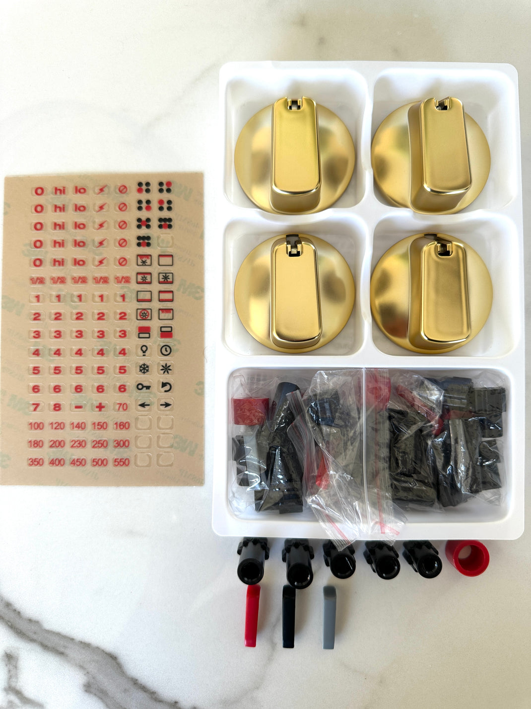 Flat lay of box contents: 4 premium knobs, indicator inserts, universal connectors, install guide